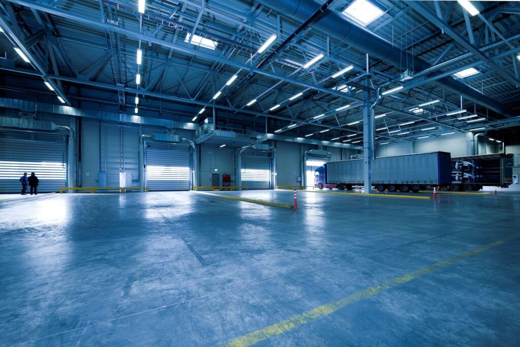 pexels photo 257636 257636 Wide view of an empty modern warehouse with industrial lighting and trucks.