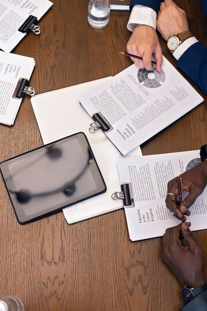 services-01 Top view of a business meeting with hands, tablets, and documents on a table.